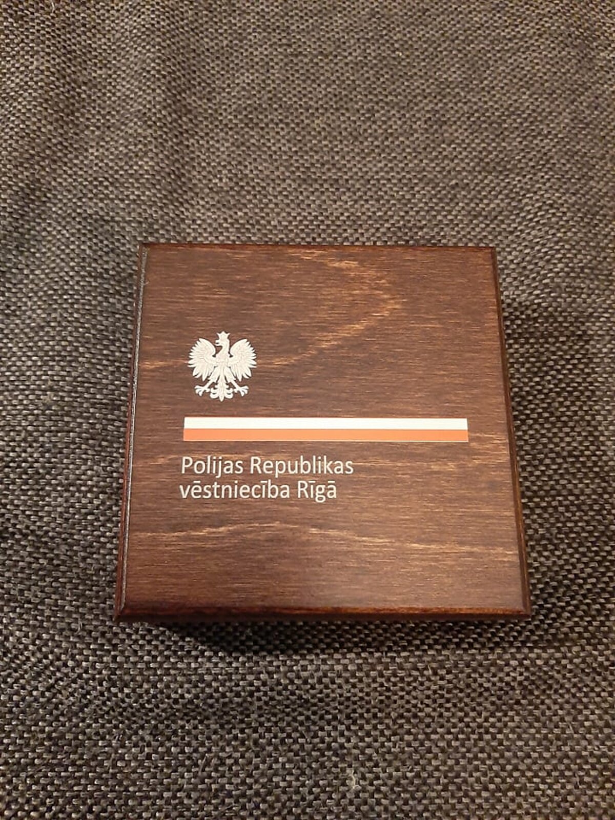 Polijas-Latvijas attiecību Simtgades medaļas koka kastīte. Foto autors (Rūdolfs Rubenis, LU Muzeja krājuma glabātājs) Polijas-Latvijas attiecību Simtgades medaļas koka kastīte. Foto autors (Rūdolfs Rubenis, LU Muzeja krājuma glabātājs)